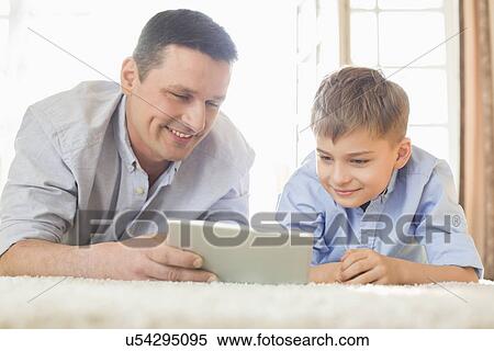 Father and son using digital table on floor at home View Large Photo Image Stock Photography - Father and son using digital table on floor at home. Fotosearch
