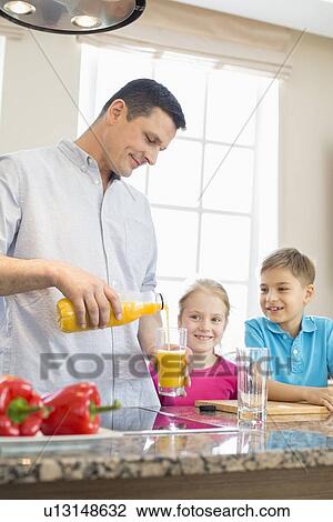 Father serving orange juice for children in kitchen View Large Photo Image Stock Image - Father serving orange juice for children in kitchen. Fotosearch