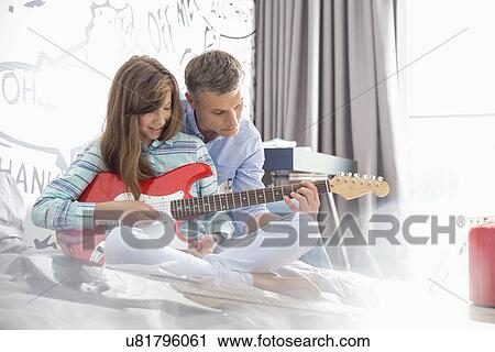 Father teaching daughter to play electric guitar at home View Large Photo Image Stock Image - Father teaching daughter to play electric guitar at home. Fotosearch