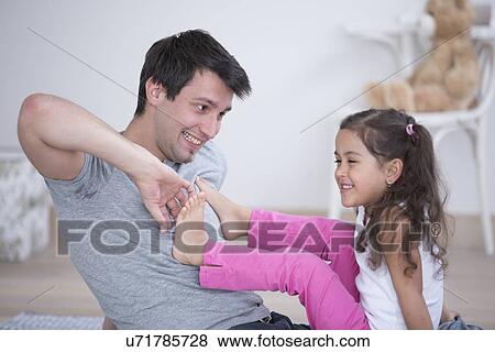 Father tickling daughter's foot at home View Large Photo Image Stock Photo - Father tickling daughter's foot at home. Fotosearch