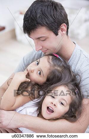 Father with daughters relaxing at home View Large Photo Image Stock Photograph - Father with daughters relaxing at home. Fotosearch