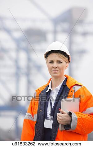 Stock Image - Female engineer holding tablet PC in shipping yard. Fotosearch