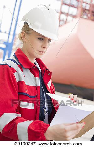 Female engineer reading documents in shipping yard View Large Photo Image Stock Photo - Female engineer reading documents in shipping yard. Fotosearch