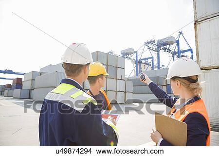 Picture - Female supervisor discussing with workers in shipping yard. Fotosearch