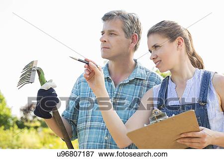 Stock Photo - Female supervisor explaining something to gardener at plant nursery. Fotosearch