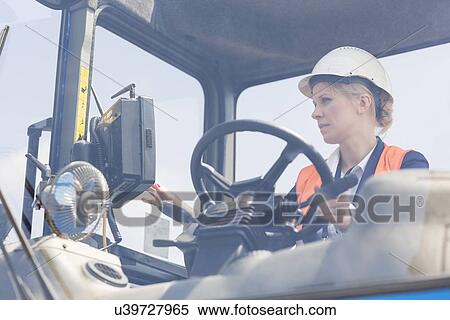 Stock Photography - Female worker operating forklift truck in shipping yard. Fotosearch