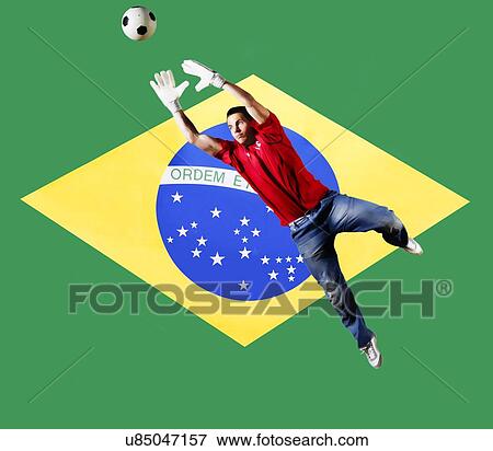 Stock Photo - Football Goalkeeper saving shot in front of Brazil National Flag. Fotosearch