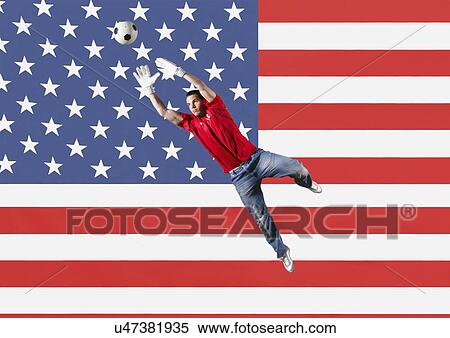 Stock Photography - Football Goalkeeper saving shot in front of USA National Flag. Fotosearch