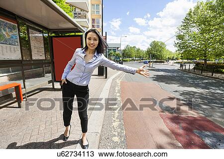 Stock Image - Full length beautiful businesswoman hailing taxi on street. Fotosearch