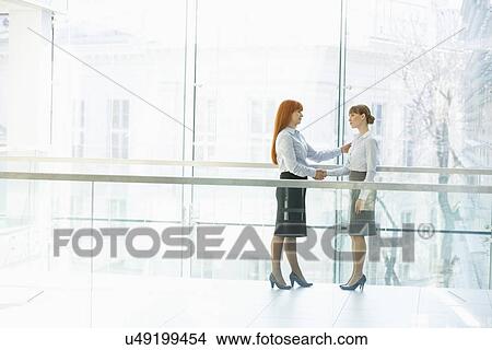 Full-length businesswomen shaking hands in office View Large Photo Image Picture - Full-length businesswomen shaking hands in office. Fotosearch