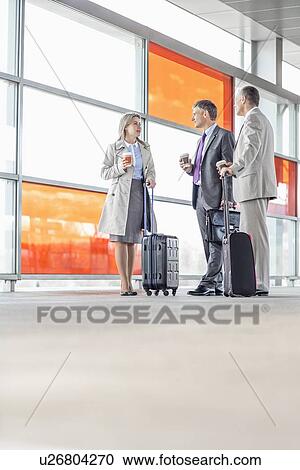 Stock Image - Full length of businesspeople talking on railroad platform. Fotosearch