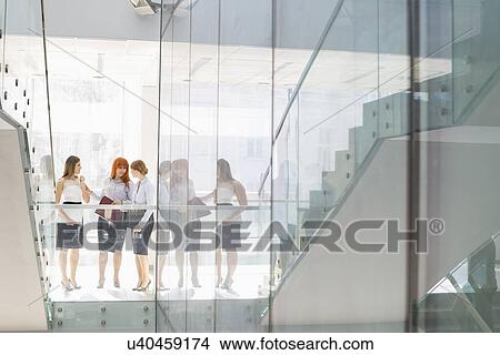 Picture - Full-length of businesswomen conversing in office. Fotosearch