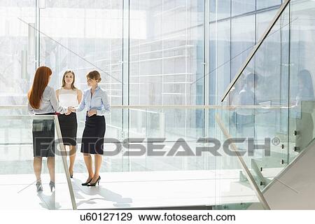 Stock Photo - Full-length of businesswomen shaking hands in office. Fotosearch