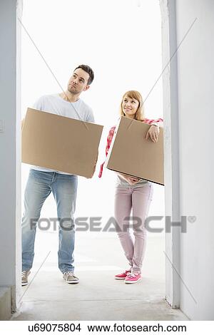 Picture - Full-length of couple with cardboard boxes standing in front of entrance. Fotosearch
