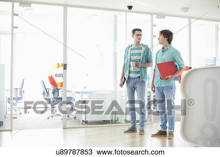 Full-length of creative businessmen conversing at office View Large Photo Image Stock Image - Full-length of creative businessmen conversing at office. Fotosearch