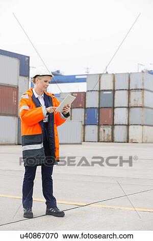 Full-length of female engineer using tablet computer in shipping yard View Large Photo Image Stock Image - Full-length of female engineer using tablet computer in shipping yard. Fotosearch