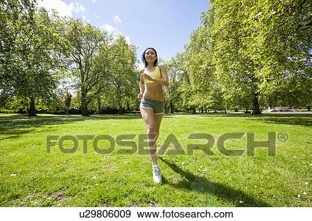 Full length of fit woman jogging at park View Large Photo Image Stock Photo - Full length of fit woman jogging at park. Fotosearch