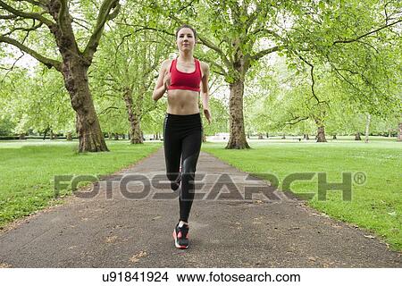 Picture - Full length of fit young woman jogging in park. Fotosearch