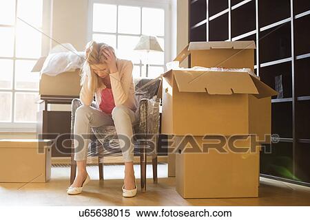 Full-length of frustrated woman sitting by cardboard boxes in new house View Large Photo Image Stock Photography - Full-length of frustrated woman sitting by cardboard boxes in new house. Fotosearch