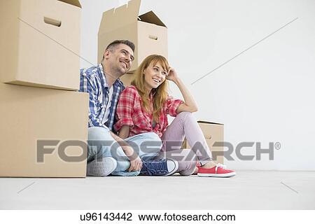 Full-length of happy couple sitting in new house View Large Photo Image Stock Image - Full-length of happy couple sitting in new house. Fotosearch
