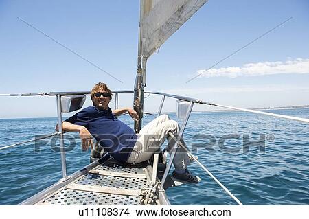 Full-length of happy man sitting on bow of yacht View Large Photo Image Picture - Full-length of happy man sitting on bow of yacht. Fotosearch