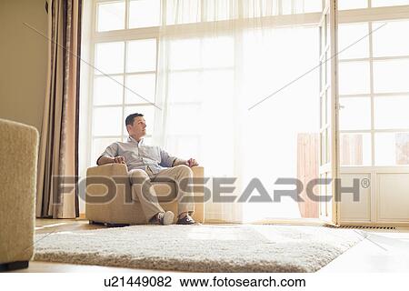 Full length of man relaxing on armchair at home View Large Photo Image Stock Image - Full length of man relaxing on armchair at home. Fotosearch