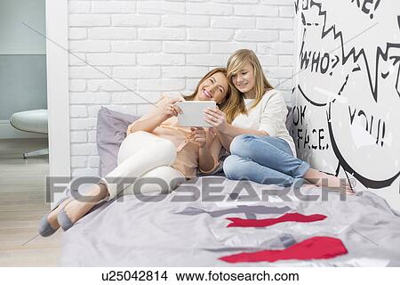 Picture - Full-length of mother with daughter using tablet PC in bedroom. Fotosearch