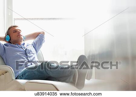 Stock Photography - Full-length of relaxed Middle-aged man listening to music at home. Fotosearch