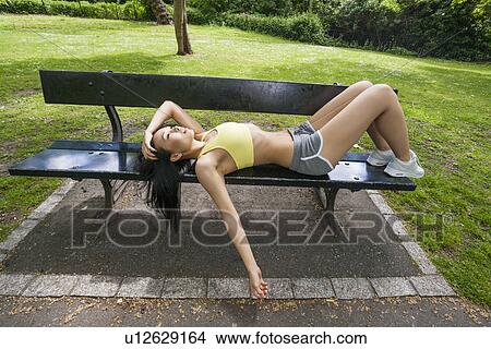 Picture - Full length of tired fit woman relaxation on beach in park. Fotosearch