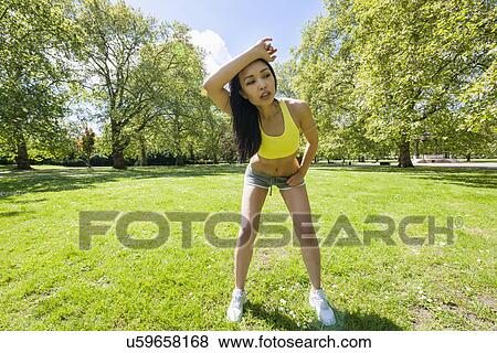 Full length of tired young woman looking away while exercising in park View Large Photo Image Stock Photo - Full length of tired young woman looking away while exercising in park. Fotosearch