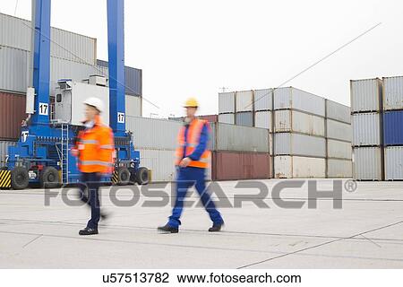 Full-length of workers walking in shipping yard View Large Photo Image Stock Image - Full-length of workers walking in shipping yard. Fotosearch