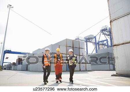 Stock Photograph - Full-length of workers walking in shipping yard. Fotosearch