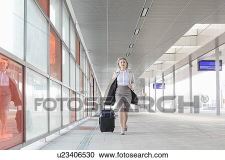 Full length of young businesswoman with luggage rushing in railroad station View Large Photo Image Stock Image - Full length of young businesswoman with luggage rushing in railroad station. Fotosearch