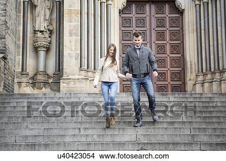 Picture - Full length of young couple moving down steps against building. Fotosearch