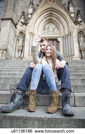 Full length of young couple taking selfie while sitting on steps outdoors View Large Photo Image Stock Photograph - Full length of young couple taking selfie while sitting on steps outdoors. Fotosearch