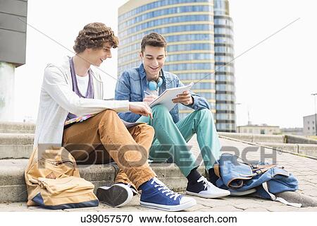 Full length of young male college students studying on steps against building View Large Photo Image Stock Image - Full length of young male college students studying on steps against building. Fotosearch