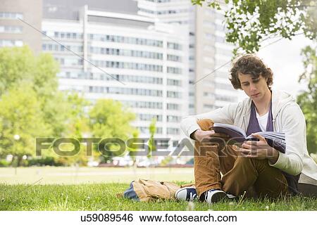 Full length of young man reading book on college campus View Large Photo Image Stock Photograph - Full length of young man reading book on college campus. Fotosearch