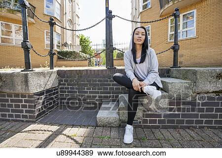 Full length portrait of confident young woman sitting on stairs against building View Large Photo Image Stock Photo - Full length portrait of confident young woman sitting on stairs against building. Fotosearch