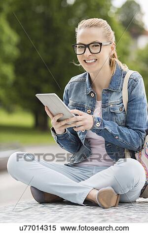Full length portrait of smiling young female college student using tablet PC in park View Large Photo Image Stock Photography - Full length portrait of smiling young female college student using tablet PC in park. Fotosearch