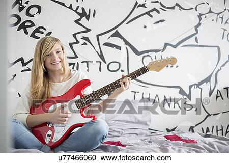 Full-length portrait of teenage girl playing guitar in bedroom View Large Photo Image Stock Image - Full-length portrait of teenage girl playing guitar in bedroom. Fotosearch