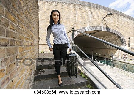 Full length portrait of young businesswoman with luggage walking down stairs View Large Photo Image Picture - Full length portrait of young businesswoman with luggage walking down stairs. Fotosearch