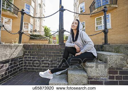 Full length portrait of young woman sitting on stairs against building View Large Photo Image Stock Image - Full length portrait of young woman sitting on stairs against building. Fotosearch