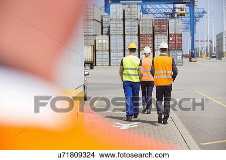 Full-length rear view of workers walking in shipping yard View Large Photo Image Picture - Full-length rear view of workers walking in shipping yard. Fotosearch