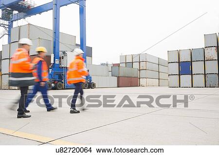 Picture - Full-length rear view of workers walking in shipping yard. Fotosearch