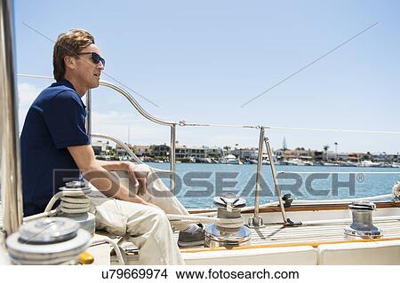 Full-length side view of man sitting on yacht View Large Photo Image Picture - Full-length side view of man sitting on yacht. Fotosearch