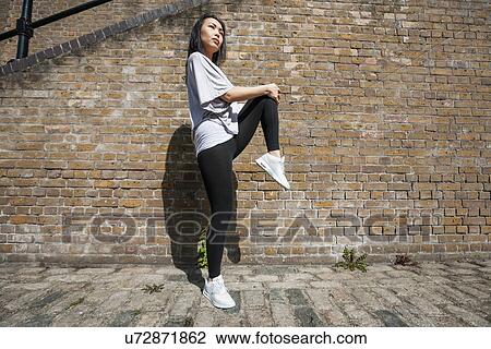 Full length side view of young fit woman stretching against brick wall View Large Photo Image Stock Image - Full length side view of young fit woman stretching against brick wall. Fotosearch