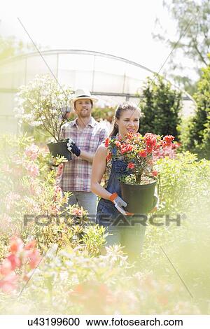 Gardeners holding potted plants outside greenhouse View Large Photo Image Stock Image - Gardeners holding potted plants outside greenhouse. Fotosearch