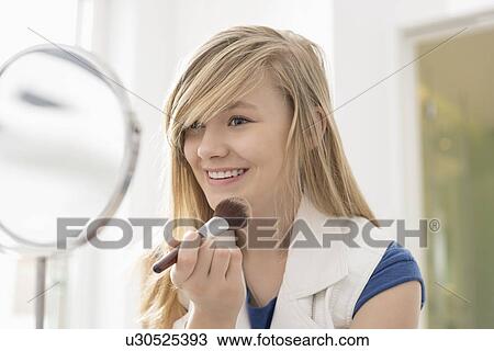 Girl applying makeup in front of mirror at home View Large Photo Image Stock Image - Girl applying makeup in front of mirror at home. Fotosearch