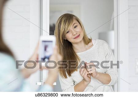 Girl photographing sister through smart phone at home View Large Photo Image Stock Image - Girl photographing sister through smart phone at home. Fotosearch