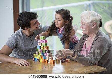Girl playing with alphabet blocks by father and grandmother at table in house View Large Photo Image Stock Photography - Girl playing with alphabet blocks by father and grandmother at table in house. Fotosearch